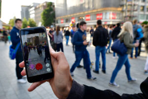 HANOVER, GERMANY - JULY 15: A young players holds his smartphone while playing "Pokemon Go" on July 15, 2016 in Hanover, Germany. 1.200 players have participated in the night walk through the city centre until midnight. "Pokemon Go" is a mobile game for smartphones, it uses advanced reality and geo-data to integrate the player in his search for new monsters or opponents within his location. The player now has to walk through the city, instead of spending time in front of a computer. (Photo by Alexander Koerner/Getty Images)