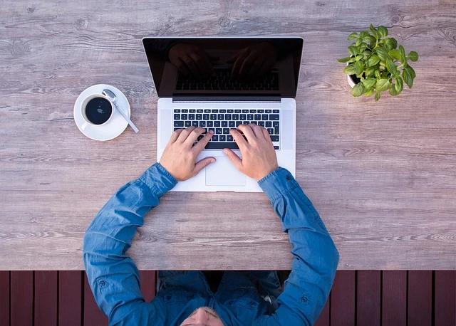 a person sitting at a table with a laptop